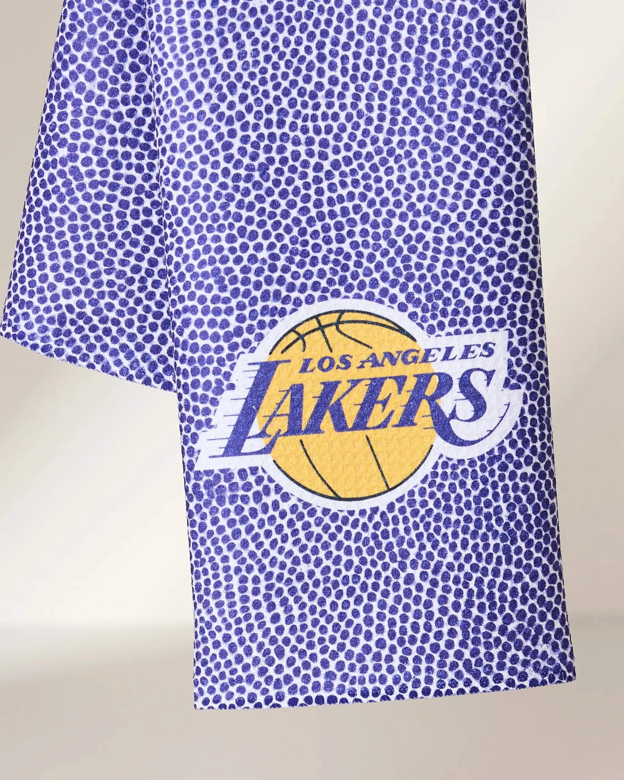 A close-up of the Geometry Lakers Grip, a purple towel with a dotted texture, featuring the Los Angeles Lakers logo with a yellow basketball and purple text on the front.