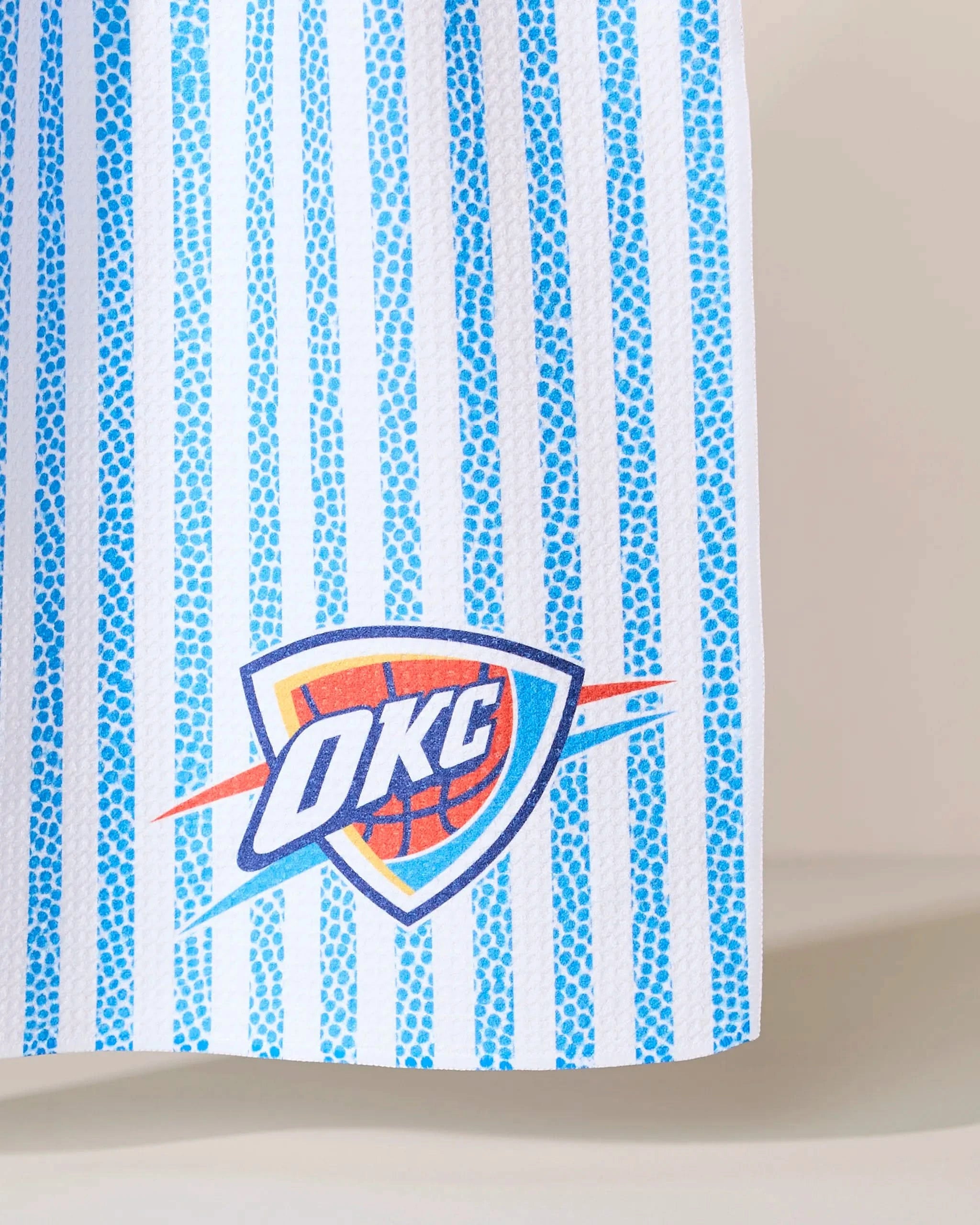 A close-up of the Geometry OKC Grip Stripe, featuring blue and white vertical stripes with the Oklahoma City Thunder (OKC) logo near the bottom.