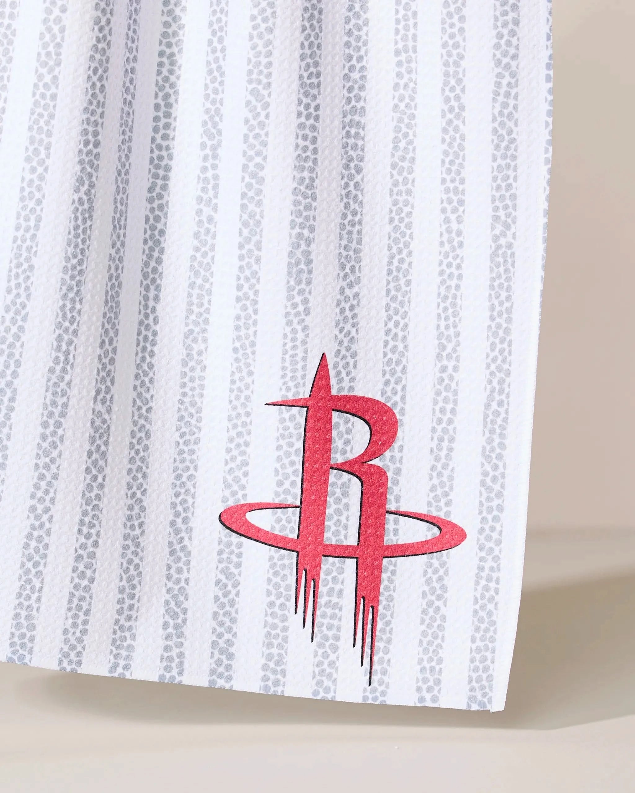 A close-up of the Geometry Rockets Grip Stripe, featuring white fabric with gray vertical stripes and a red Houston Rockets logo near the bottom right corner.
