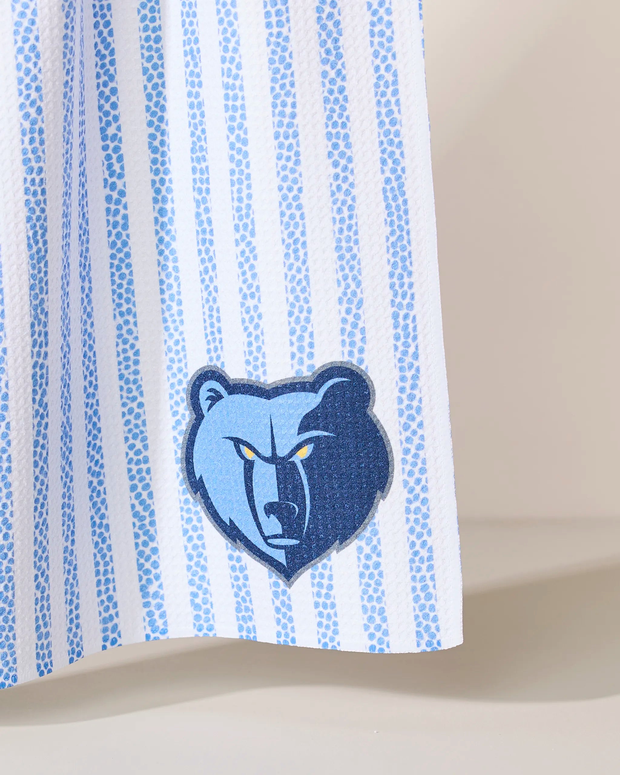 Close-up of the Geometry Grizzlies Grip Stripe fabric, featuring blue and white stripes with the Memphis Grizzlies stylized bear logo in blue and navy at the bottom.