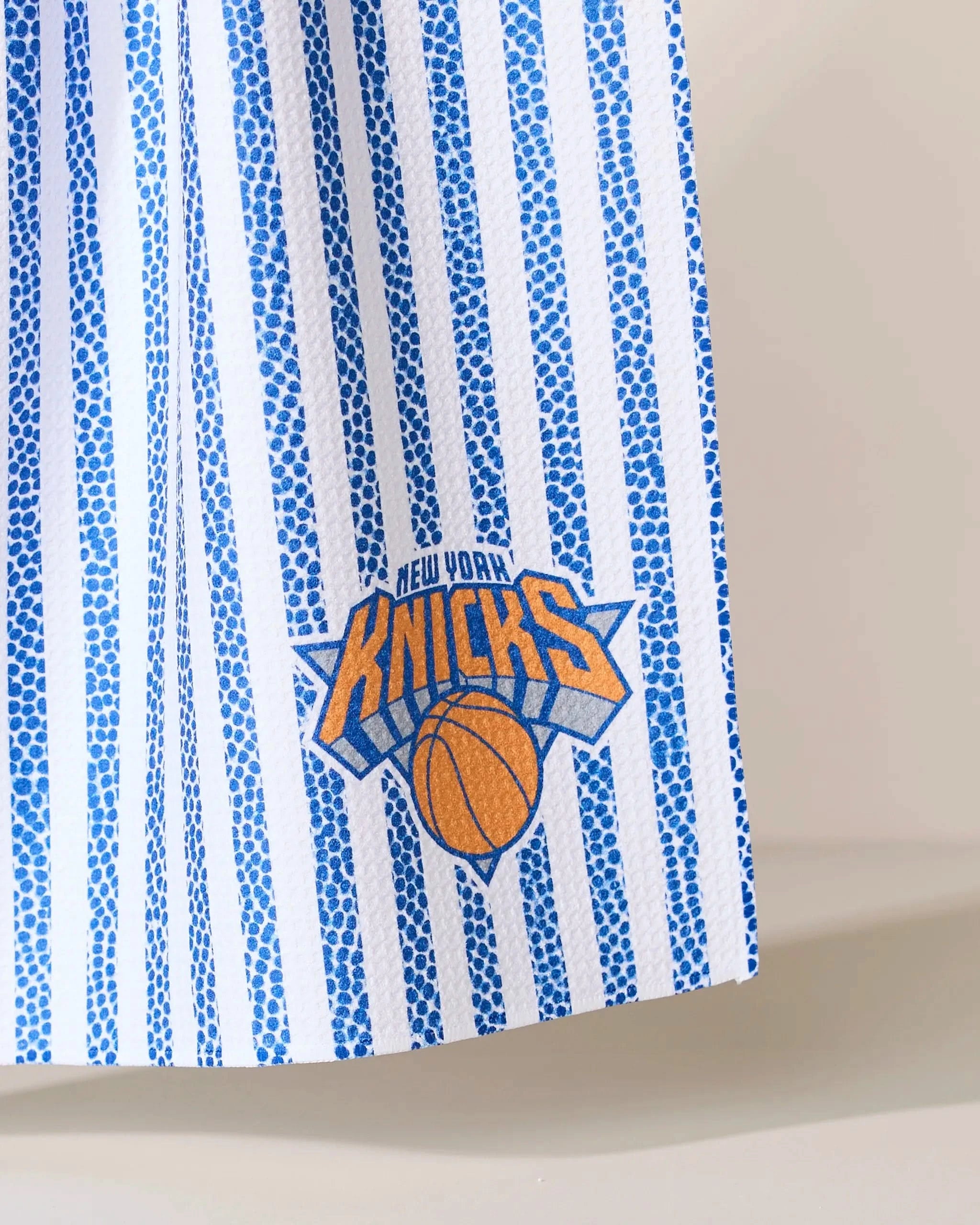 The Geometry Knicks Grip Stripe features blue and white stripes with the New York Knicks logo in orange and blue near the bottom.