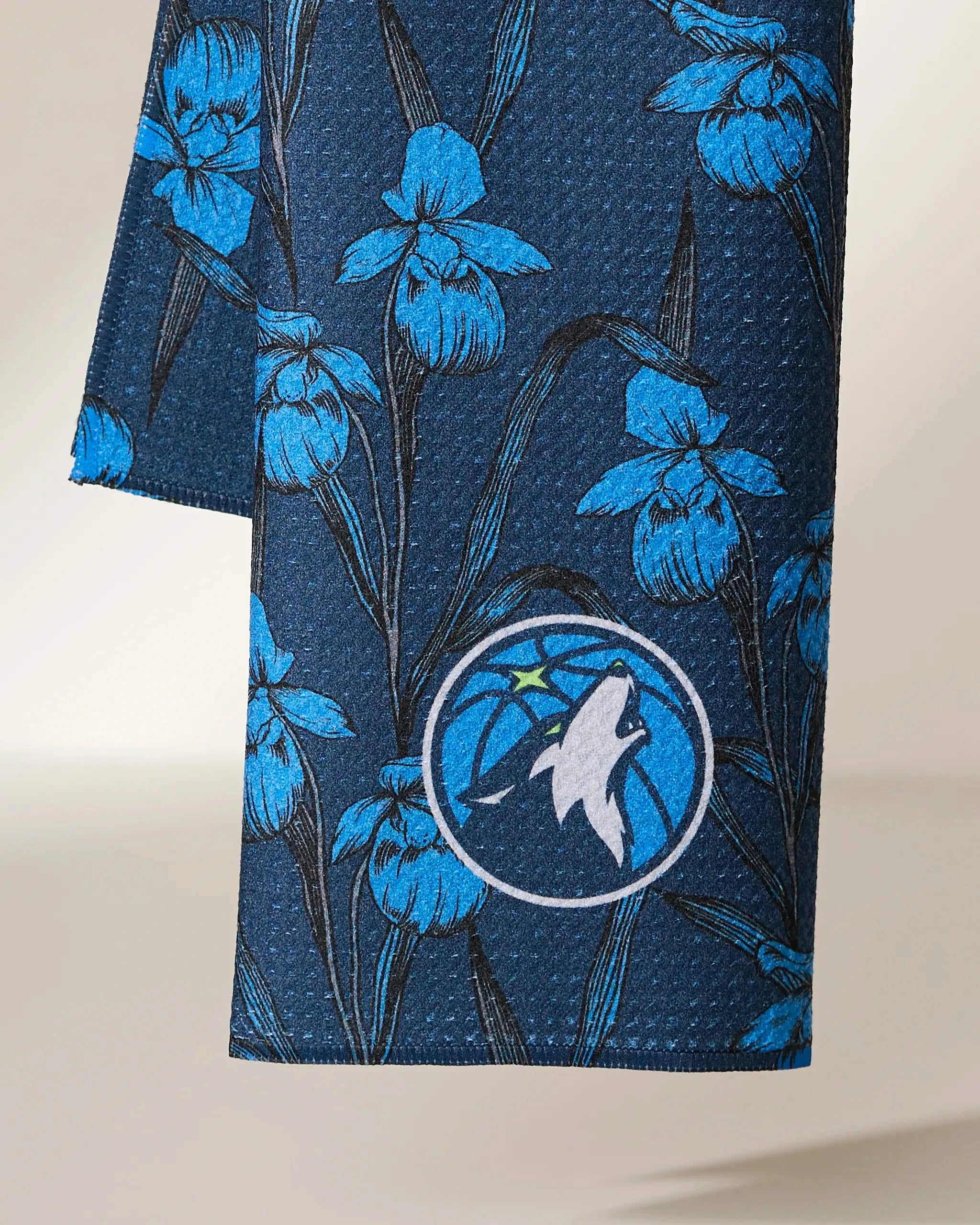 Geometry’s Timberwolves Floral: Dark blue fabric with light blue iris patterns and the Minnesota Timberwolves logo—featuring a white wolf and green star on a blue basketball background.