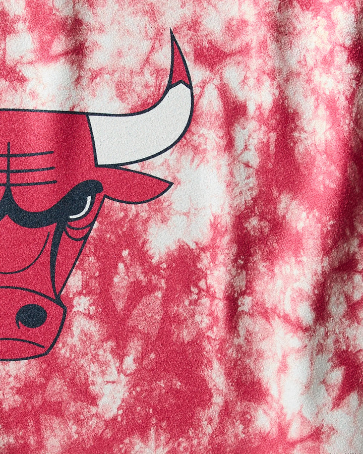 Close-up of the NBALAB x Geometry Bulls Flash fitness towel, showcasing red and white tie-dye and the left half of a fierce, stylized bull’s head with a long white horn.