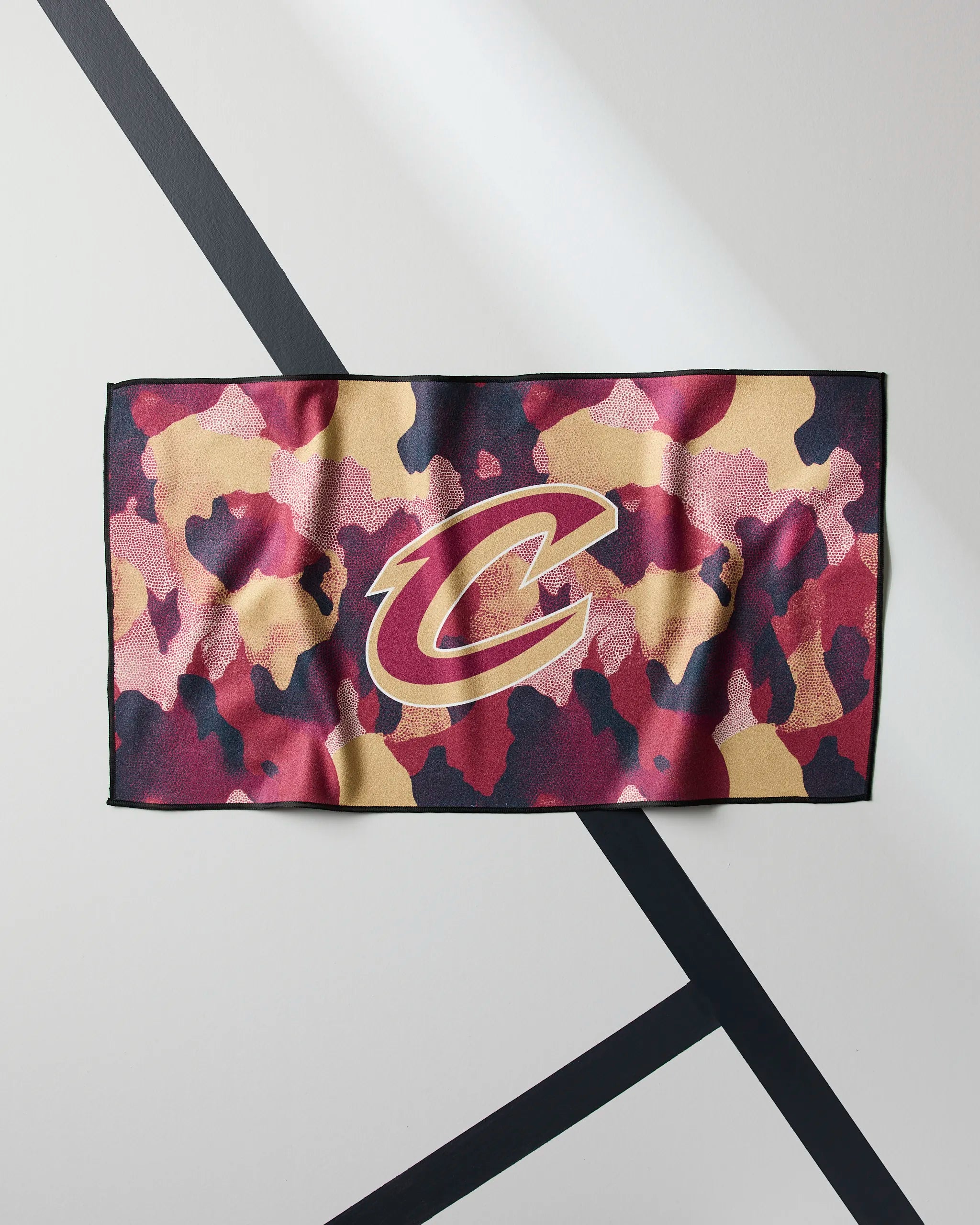 Geometry’s Cavaliers Camo is a rectangular cloth featuring a red, gold, and black camouflage pattern with a large Cleveland Cavaliers C logo in the center, set against a white background with intersecting black lines.