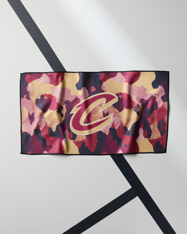 The NBALAB x Geometry Cavaliers Camo gym towel, featuring a maroon, tan, and black camouflage pattern with a large Cleveland Cavaliers logo in the center, is shown on a light background with black diagonal lines.