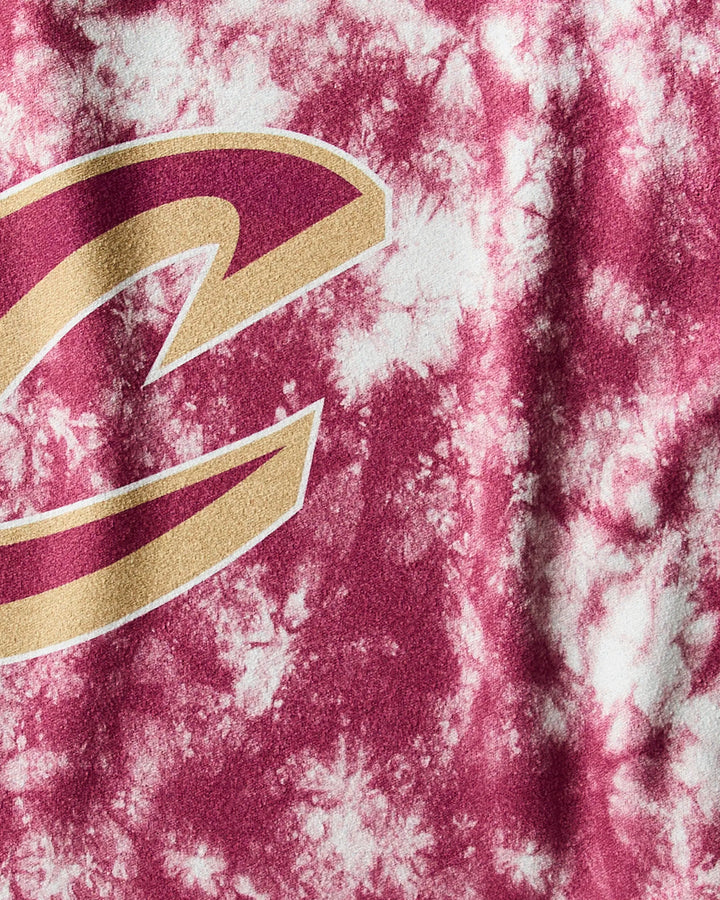 A close-up of the Cavaliers Flash fitness towel by NBALAB x Geometry, showcasing a maroon and white tie-dye design with part of a large gold and maroon C logo representing the Cleveland Cavaliers.
