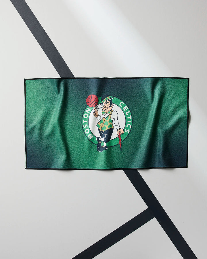 The Celtics Fade fitness towel by NBALAB x Geometry features the Boston Celtics logo with a leprechaun spinning a basketball on a green background—ideal for fans who want style and function in their gym routine.