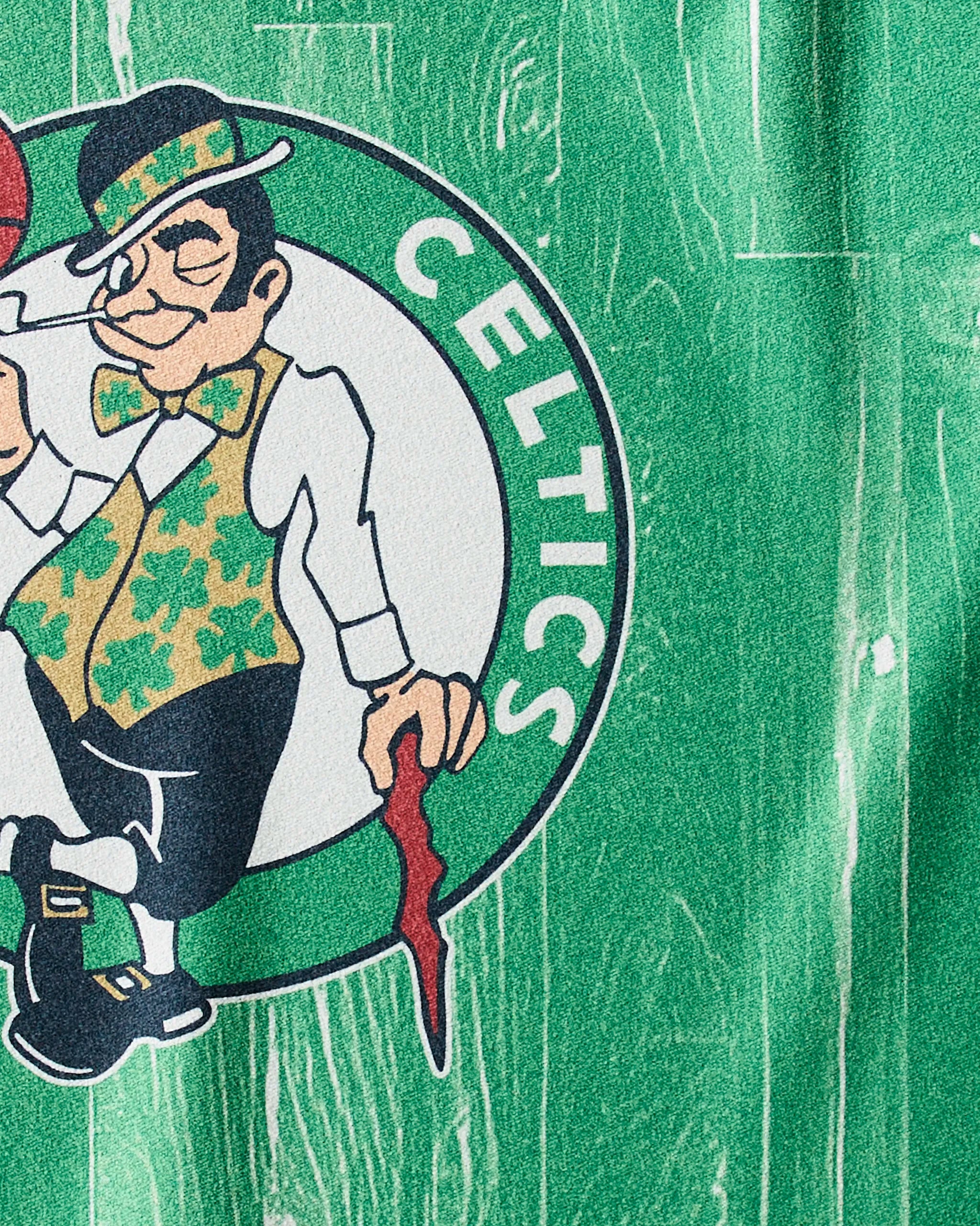 The image features the Boston Celtics leprechaun logo with a green wood-textured background—Geometry’s Celtics Zone NBA fitness towel is perfect for fans to show team spirit.