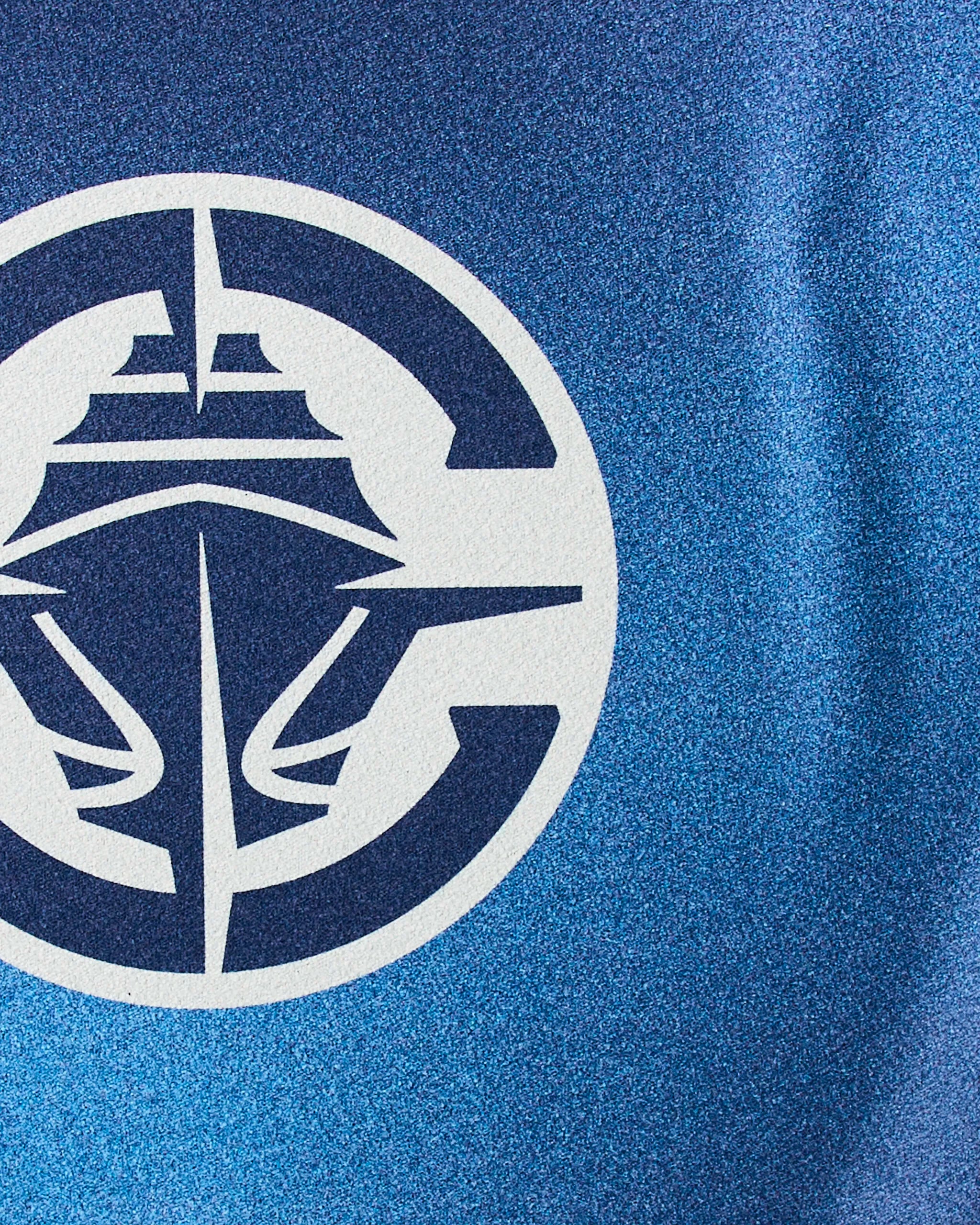 The Clippers Fade by Geometry features a stylized white ship logo with bold lines on a textured blue background, partly enclosed by a circular border—ideal for an NBA fitness towel or sustainable gym towel design.