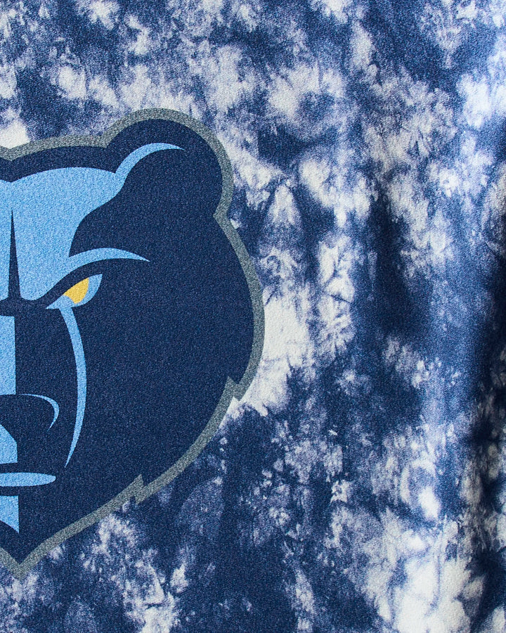 A close-up of the Grizzlies Flash bear head logo with a fierce look, yellow eye, and dark blue outline on a blue and white tie-dye sustainable workout towel by NBALAB x Geometry.