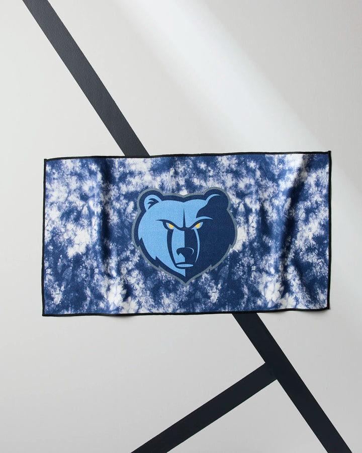 The Grizzlies Flash fitness towel by NBALAB x Geometry, featuring a blue and white tie-dye design with the Memphis Grizzlies bear logo, is displayed on a white surface with black diagonal lines.