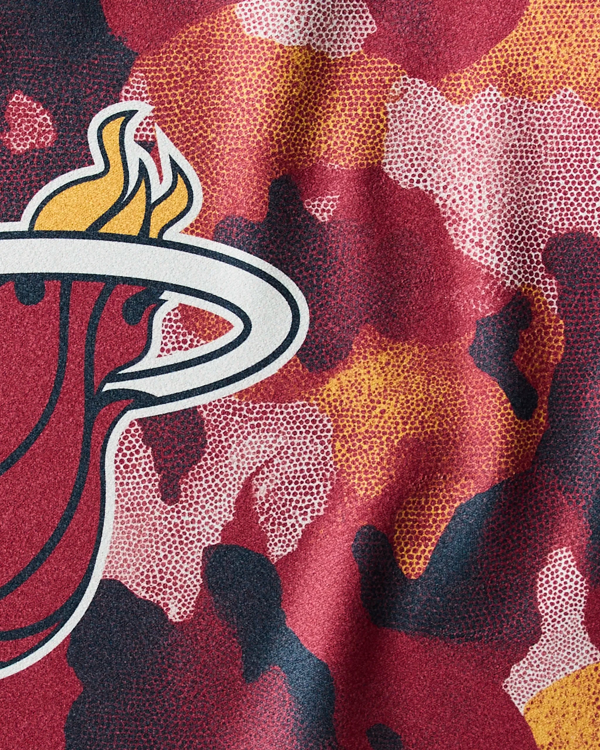 A close-up of the Geometry Heat Camo pattern—a red, orange, yellow, and black camouflage featuring part of the Miami Heat logo with flaming basketball and white hoop—perfect as an NBA-inspired fitness or quick-drying workout towel.