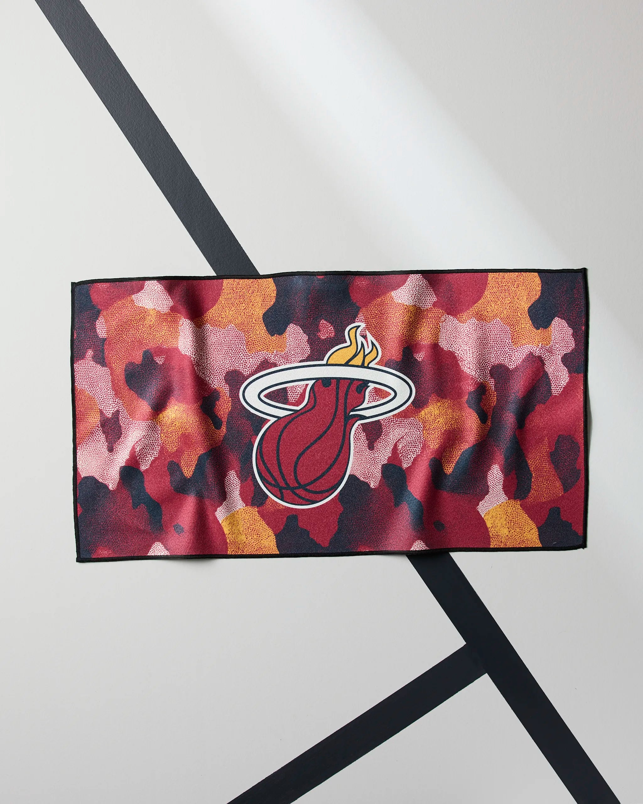 The Geometry Heat Camo towel features a red, pink, orange, and black camo pattern with the Miami Heat logo at the center—ideal for workouts or gym sessions.