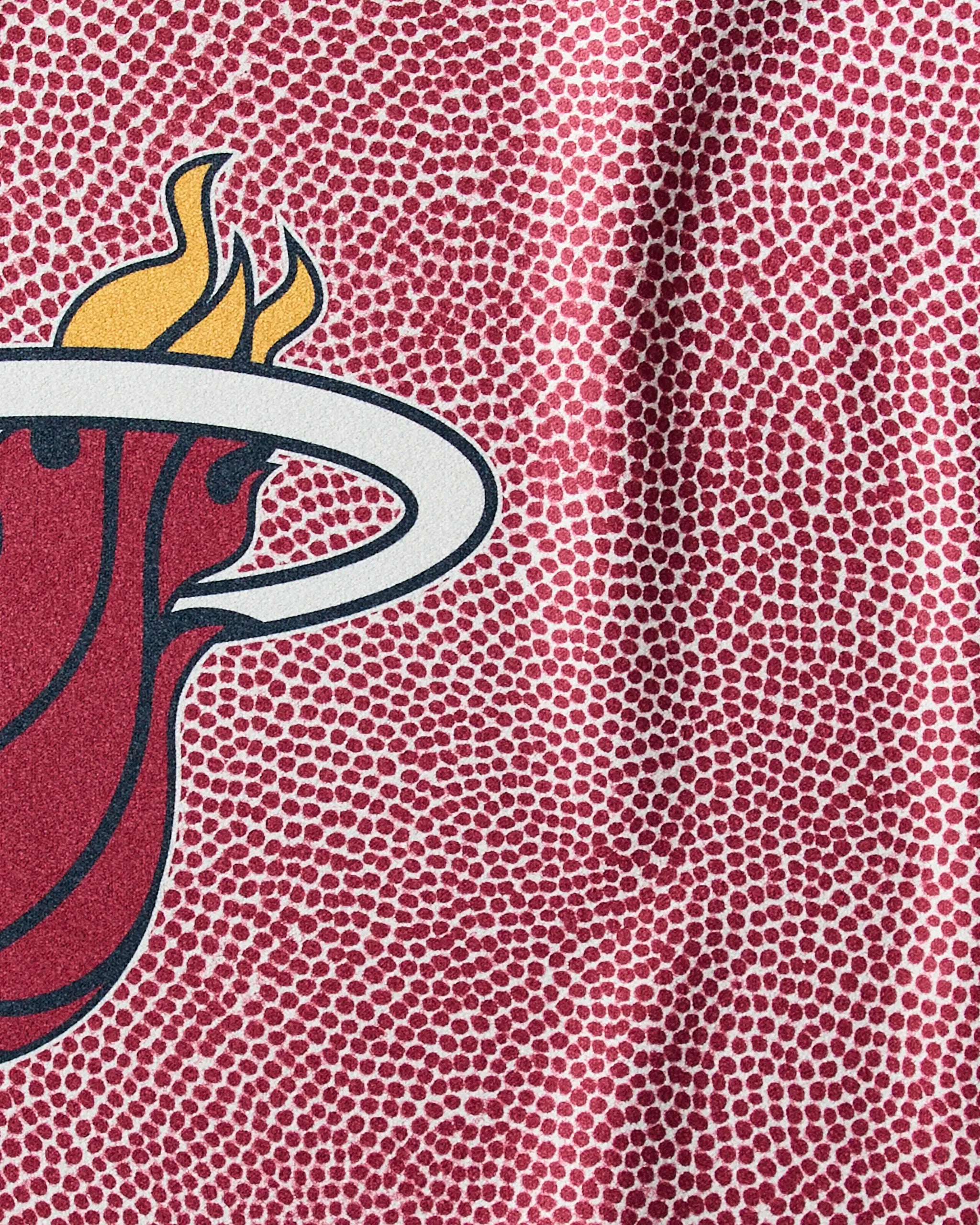Close-up of Geometry's Heat Grip quick-drying red workout towel, featuring a textured surface with dots and part of the Miami Heat logo showing a flaming basketball through a white hoop.