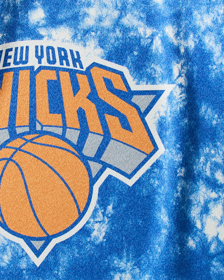 Close-up of the Knicks Flash NBA fitness towel by NBALAB x Geometry, showcasing blue and white tie-dye with the New York Knicks logo, an orange basketball, and bold orange and gray lettering.