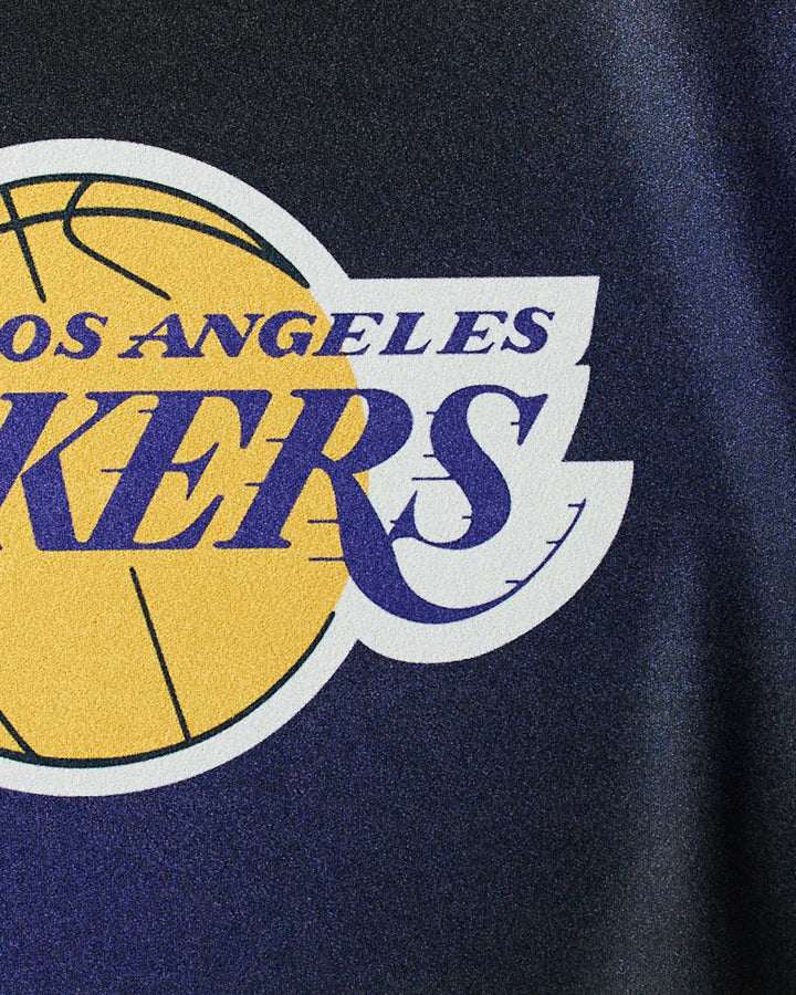 Close-up of the Lakers Fade gym towel by NBALAB x Geometry, showcasing part of a yellow basketball with purple text on a dark background—a quick-drying must-have for NBA fans.