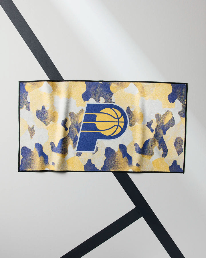 The Pacers Camo by NBALAB x Geometry is a rectangular, quick-drying workout towel with a yellow, blue, and white camo pattern and the Indiana Pacers logo centered on a light background with black diagonal lines.