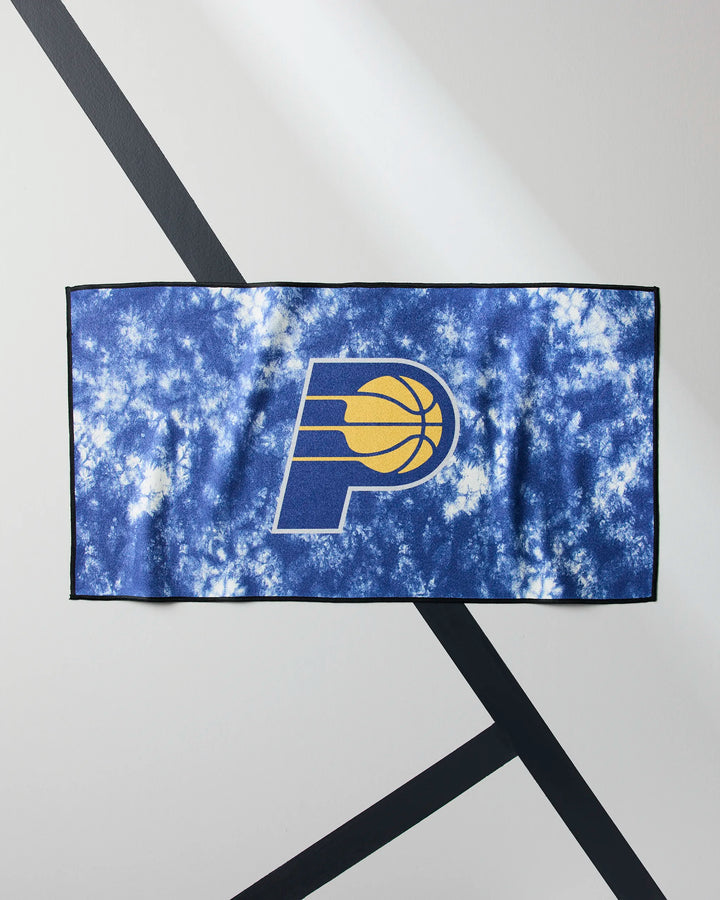 The Pacers Flash from NBALAB x Geometry is a rectangular blue and white tie-dye NBA fitness towel with the Indiana Pacers logo in the center, shown flat on a white surface with black diagonal lines.