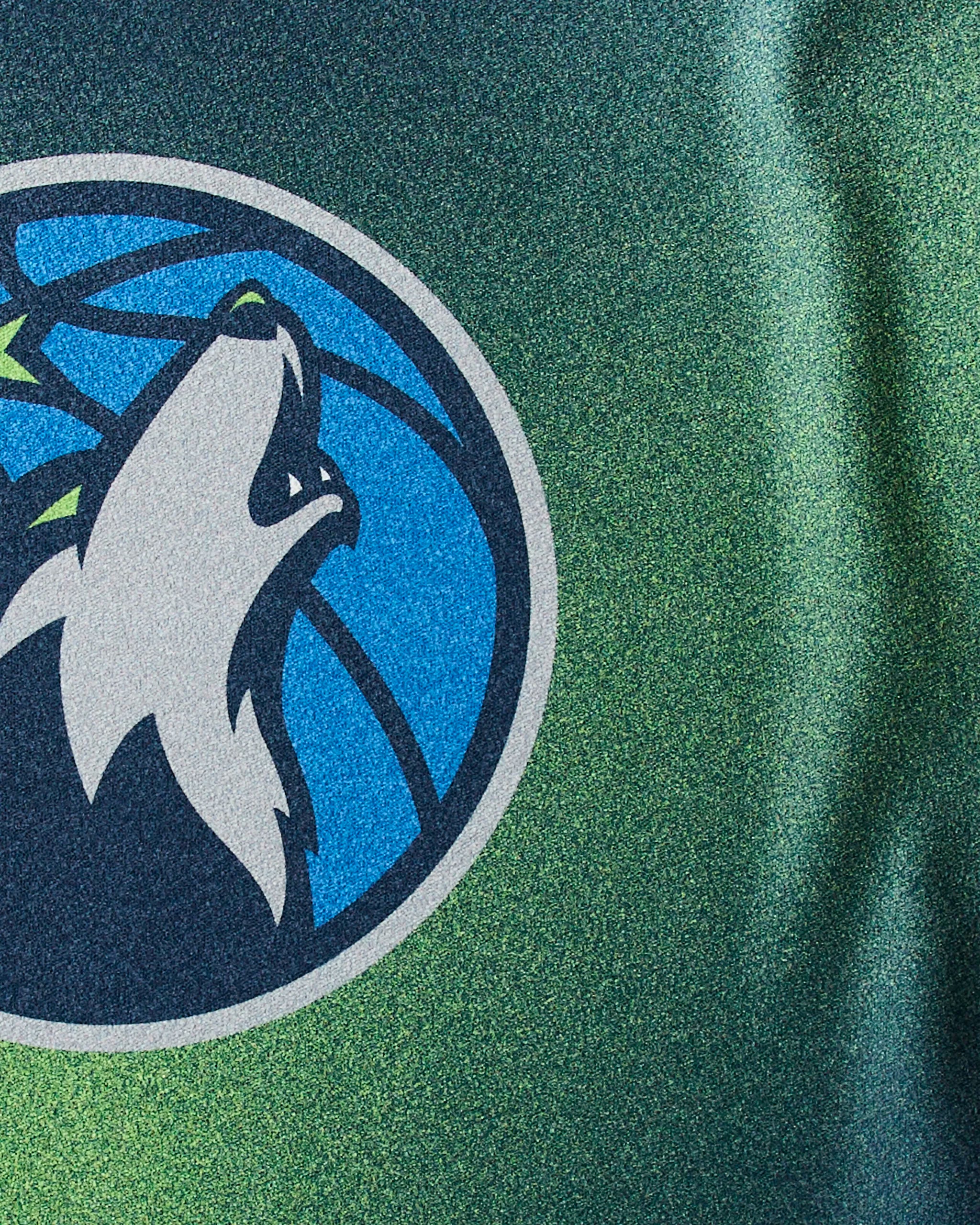 Close-up of the Timberwolves Fade sports jersey by Geometry, featuring a stylized wolf howling in front of a basketball on a blue and green background—perfect inspiration for your next workout with this sustainable towel.