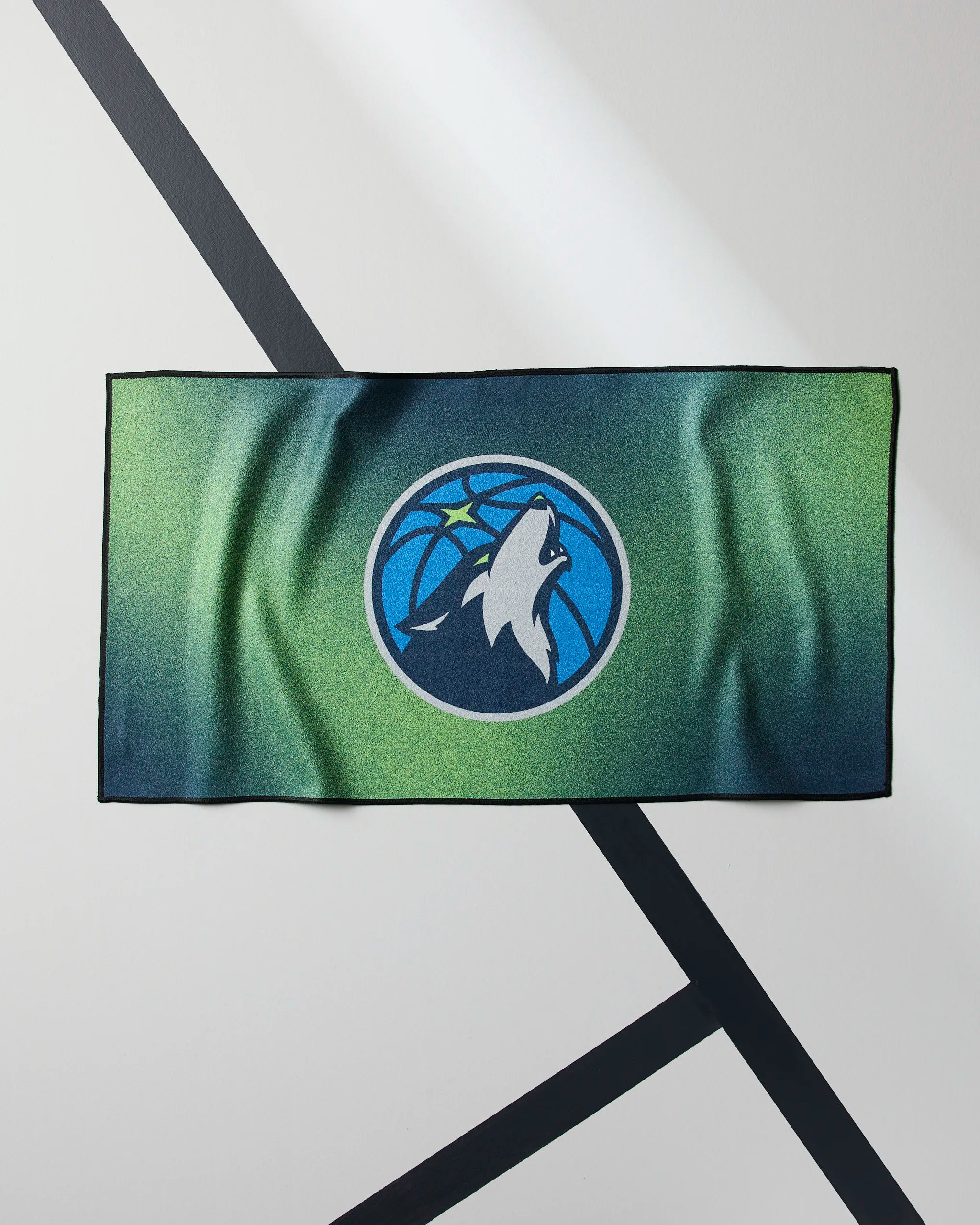The Geometry Timberwolves Fade is a quick-drying gym towel with a bold wolf logo, ideal for workouts or as your NBA fitness towel courtside.