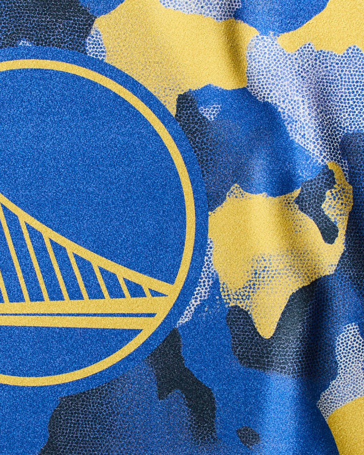 Close-up of the Warriors Camo fitness towel by NBALAB x Geometry, featuring blue, yellow, and black camouflage with part of the Golden State Warriors bridge logo in a yellow circle.