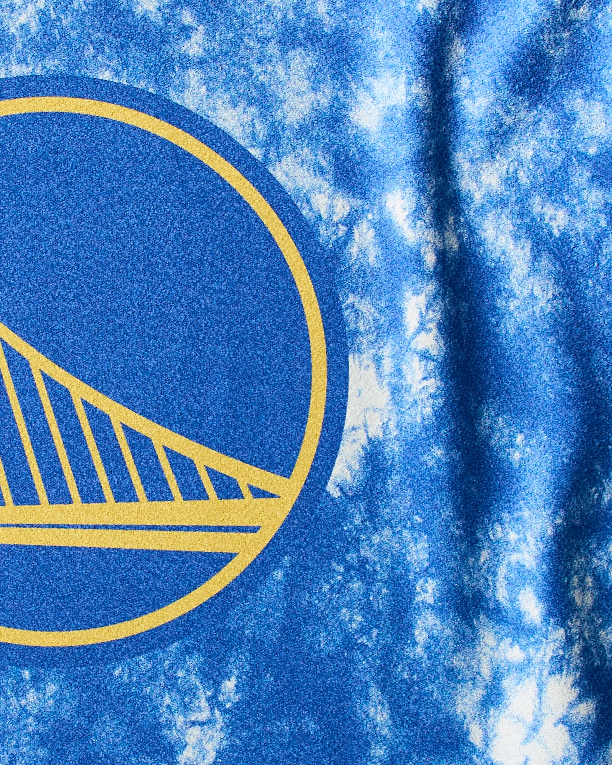 Close-up of the blue and white tie-dye Warriors Flash fitness towel by Geometry, showcasing part of the Golden State Warriors logo in yellow.