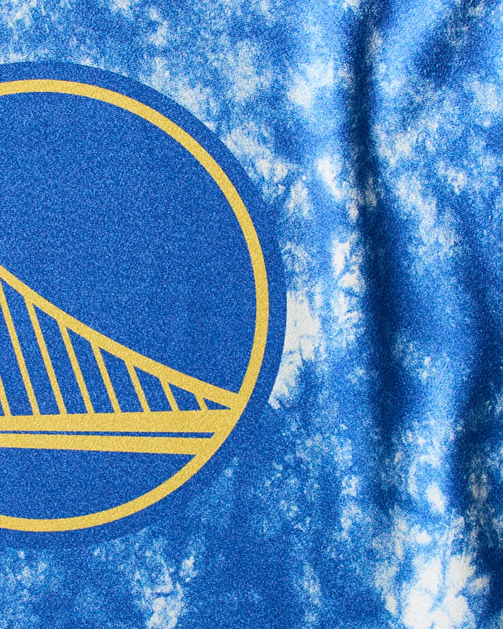 Close-up of the Warriors Flash fitness towel by NBALAB x Geometry, featuring a blue and white tie-dye design with part of the Golden State Warriors’ yellow bridge logo.