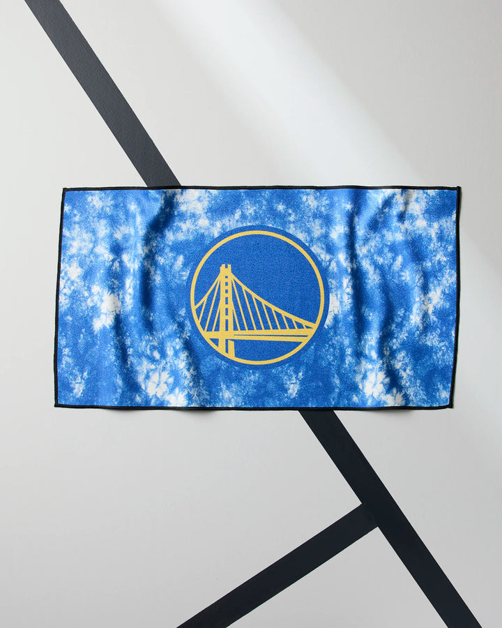 The NBALAB x Geometry Warriors Flash NBA fitness towel, in blue and white tie-dye with the Golden State Warriors' yellow bridge logo, is displayed on a light gray background with intersecting black lines.