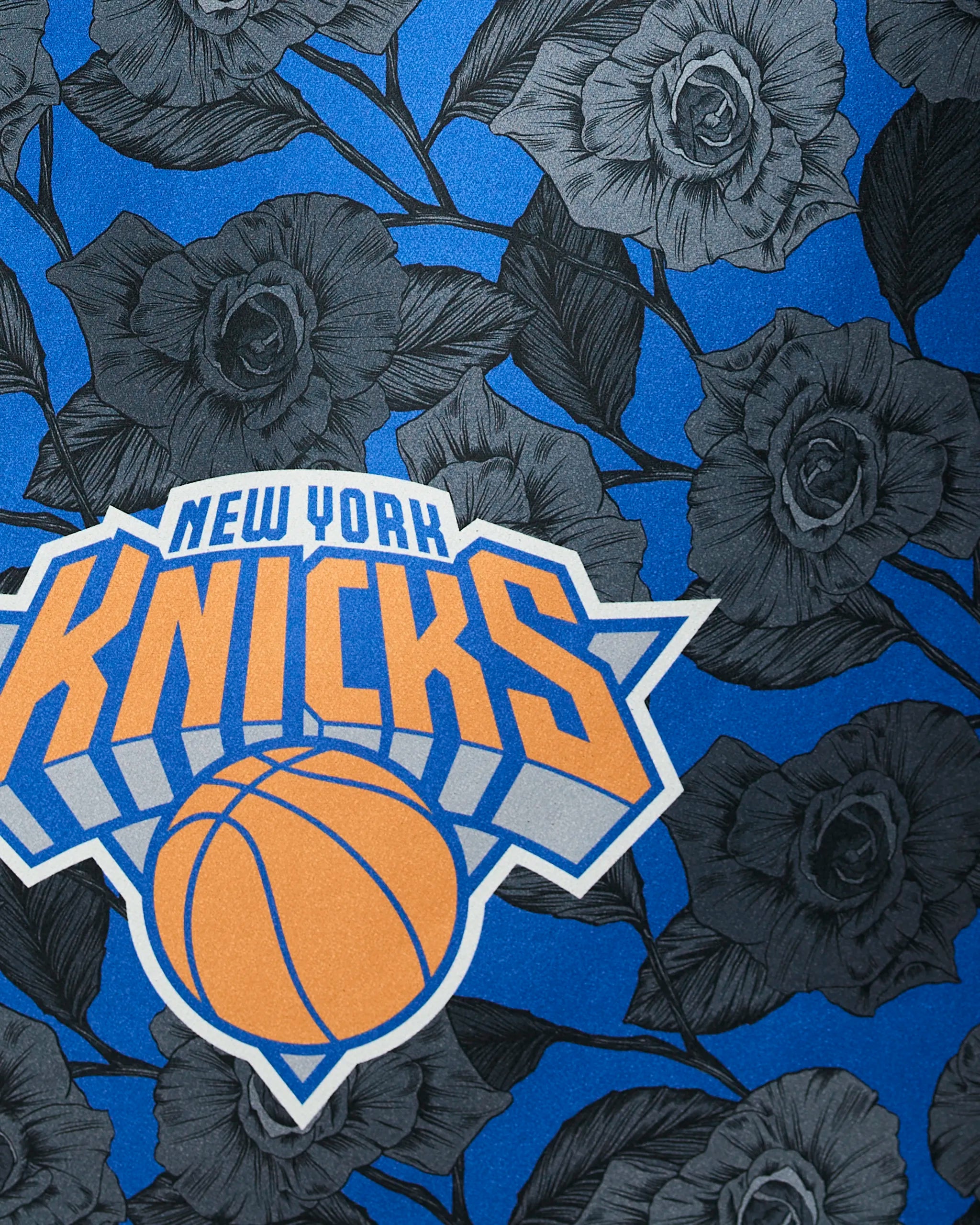 The Geometry Knicks Floral features the New York Knicks logo with an orange basketball and bold text, centered over black and gray roses on a blue background.