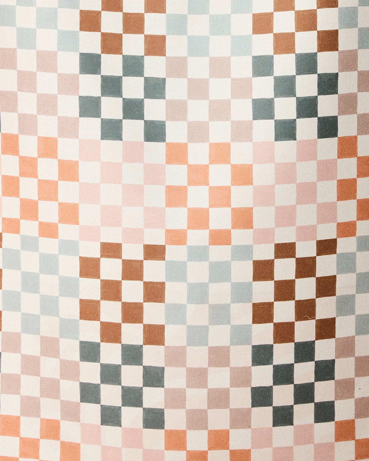 The Autumn Checkers beach towel by GEOMETRY features a repeating geometric checkered pattern with small squares in pink, brown, blue, and white on quick-drying fabric.
