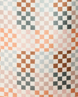 The Autumn Checkers beach towel by GEOMETRY features a repeating geometric checkered pattern with small squares in pink, brown, blue, and white on quick-drying fabric.