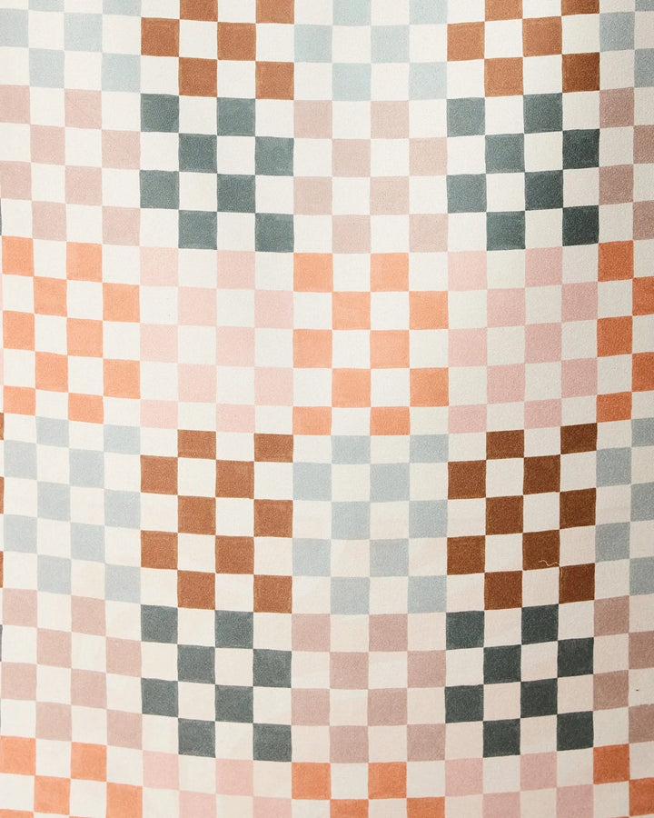 The Autumn Checkers beach towel by GEOMETRY features a repeating geometric checkered pattern with small squares in pink, brown, blue, and white on quick-drying fabric.