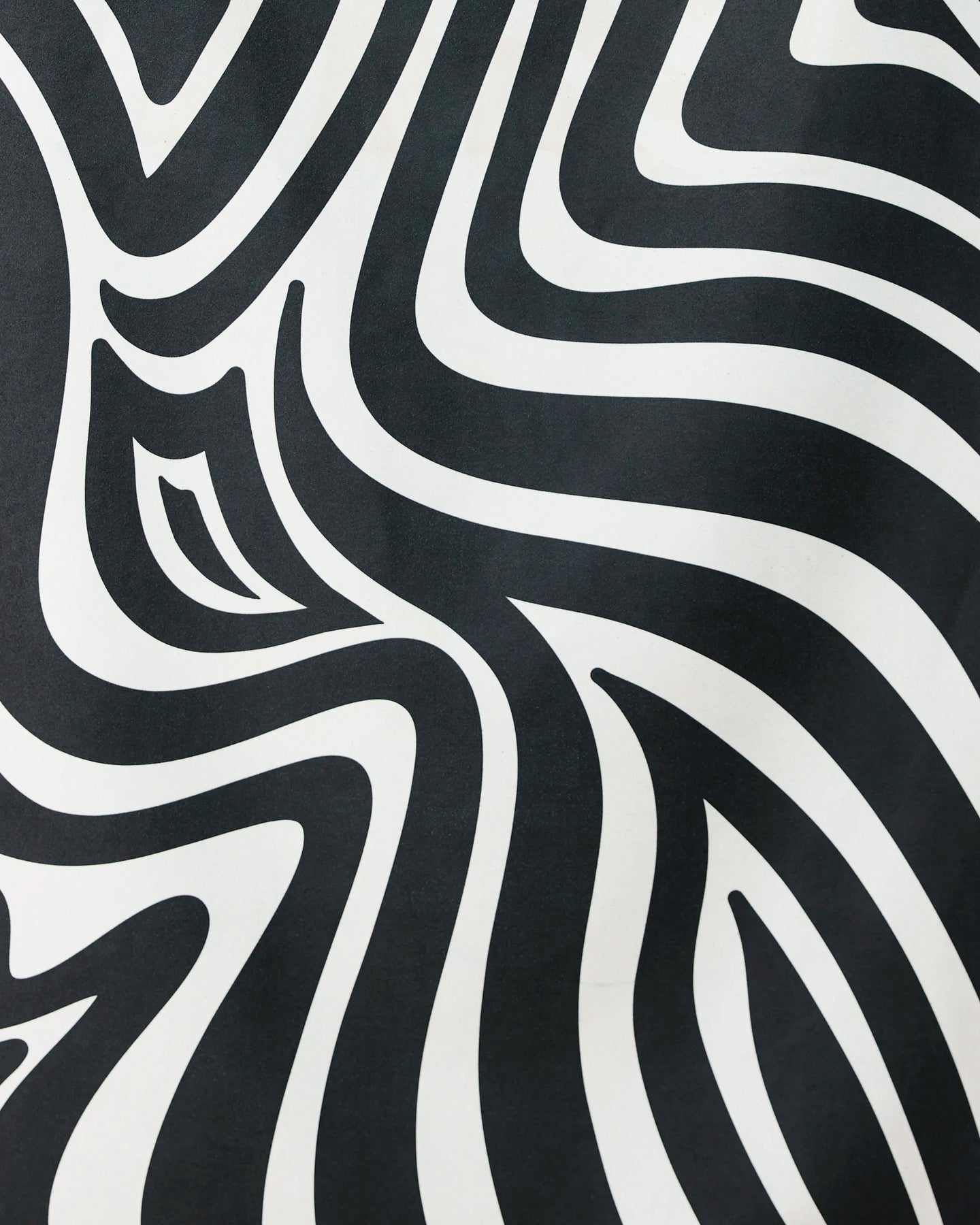 The Dizzy Black quick-drying beach towel by GEOMETRY features bold, wavy black and white zebra-like stripes, creating an eye-catching optical illusion that blends standout style with practical function.