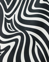 The Dizzy Black quick-drying beach towel by GEOMETRY features bold, wavy black and white zebra-like stripes, creating an eye-catching optical illusion that blends standout style with practical function.
