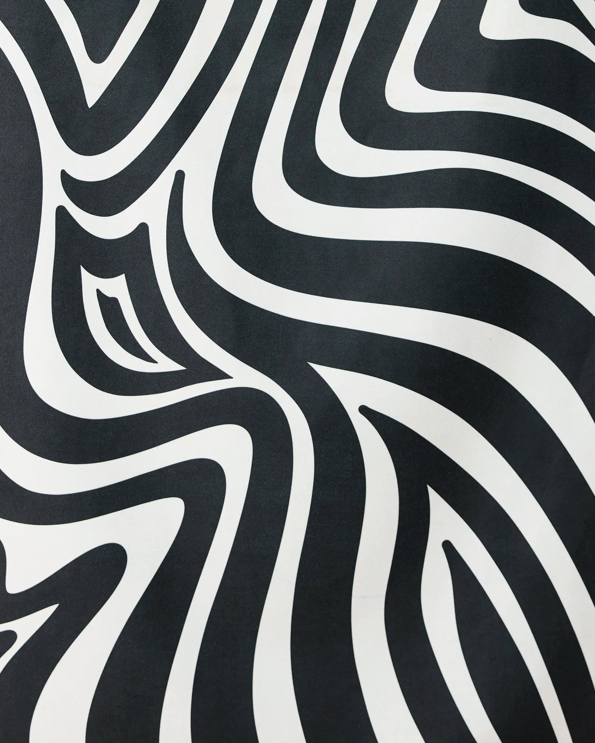 The Dizzy Black quick-drying beach towel by GEOMETRY features bold, wavy black and white zebra-like stripes, creating an eye-catching optical illusion that blends standout style with practical function.