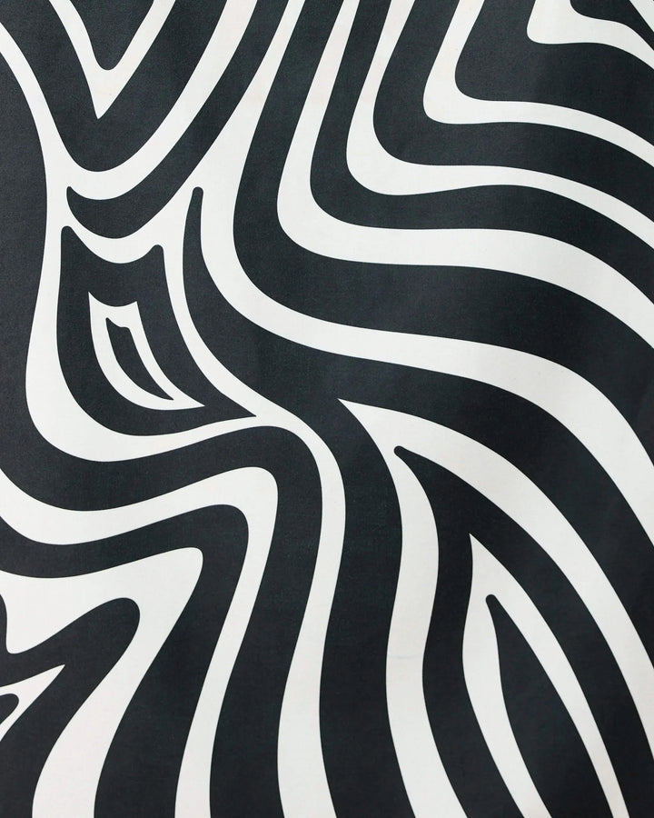 The Dizzy Black quick-drying beach towel by GEOMETRY features bold, wavy black and white zebra-like stripes, creating an eye-catching optical illusion that blends standout style with practical function.