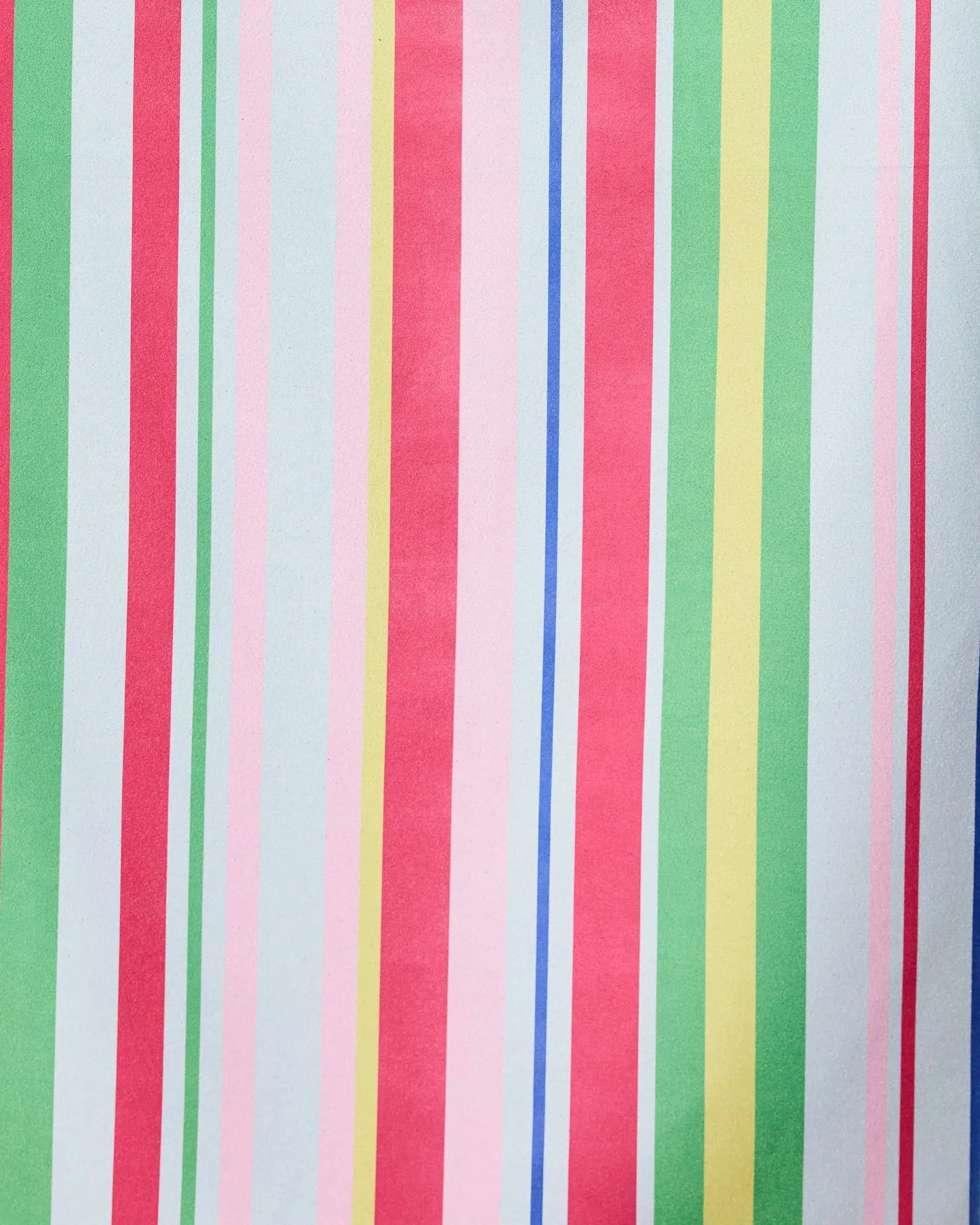 The GEOMETRY Line It Up Melon beach towel features vibrant pastel vertical stripes in pink, red, green, yellow, blue, and white on quick-drying recycled fabric for a playful look.