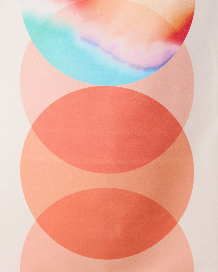 Abstract image with four vertically aligned circles: the bottom three are orange shades, while the top circle features pastel blue, pink, and peach hues in a watercolor style resembling the GEOMETRY Orange Dream towel.