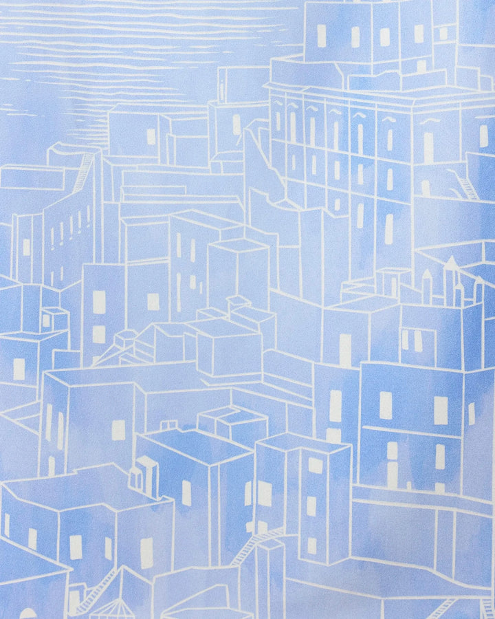 Abstract illustration of a cityscape in blue and white geometric shapes, reminiscent of the simple lines featured on the Amalfi Coast towel by GEOMETRY, set against a lightly textured sky.