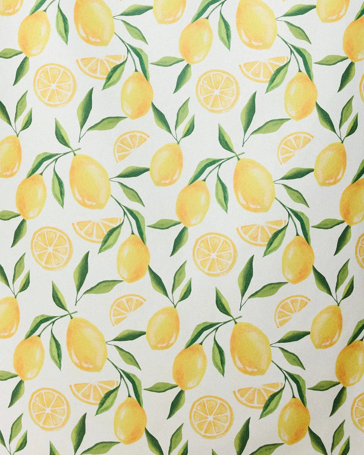 The Limoncello micro-loop beach towel by GEOMETRY features a seamless pattern of whole yellow lemons, lemon slices, and green leaves on white—crafted from recycled materials for a fresh, summery style.
