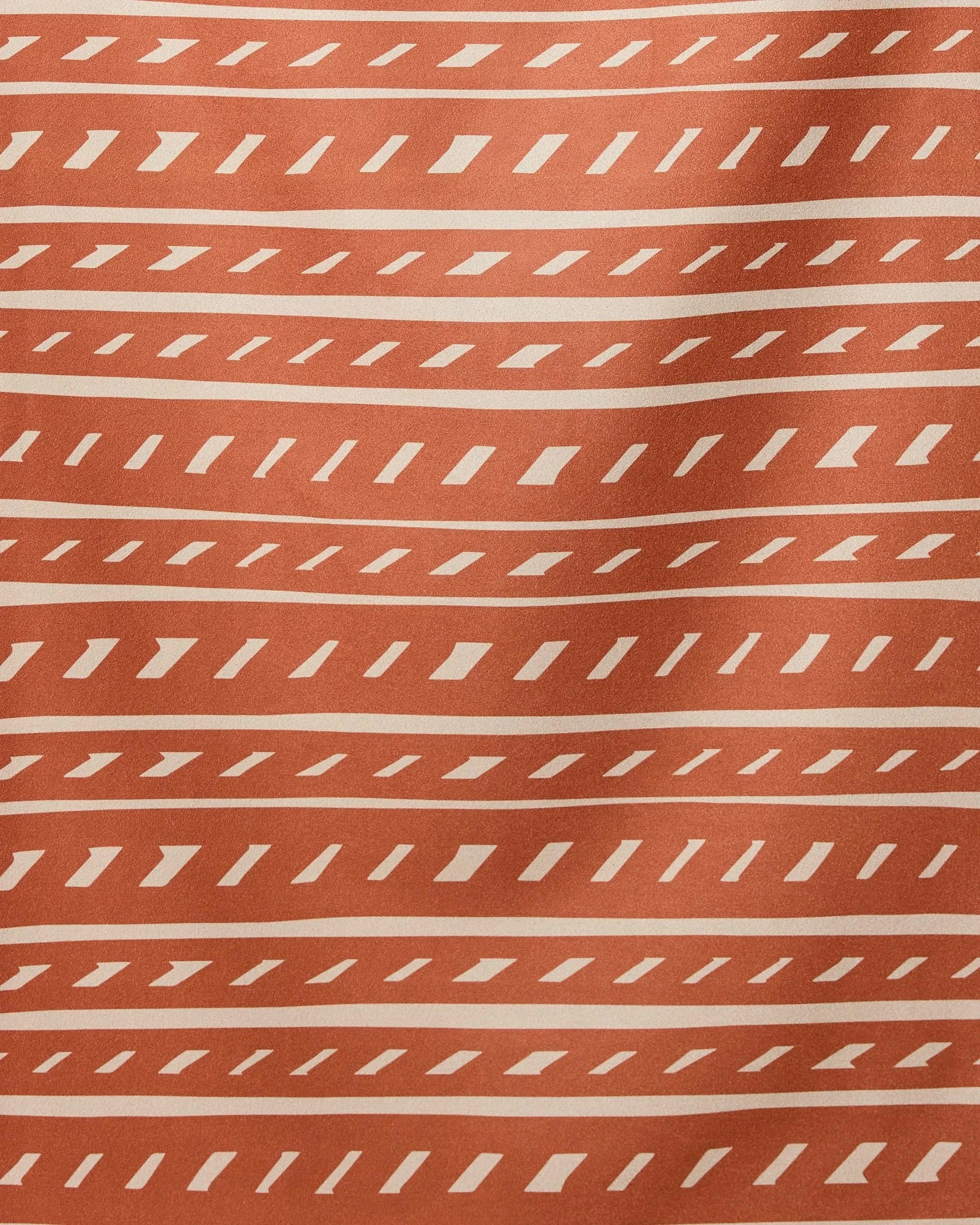 The GEOMETRY Auburn Autumn Beach Towel features a rust-orange background with cream geometric lines in horizontal rows, creating a stylish, modern pattern—perfect for anyone seeking a quick-drying beach towel.