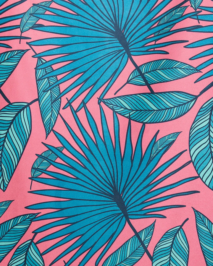 The GEOMETRY Jazzy Jungle Micro-loop beach towel features blue palm and green striped leaves on a pink background, creating a vibrant tropical pattern with quick-drying fabric.