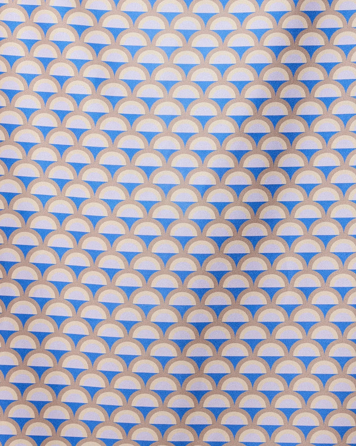 A repeating geometric pattern of overlapping mauve, beige, and white semicircles forms a scallop design on the GEOMETRY Mauve Mounds quick-drying beach towel, with diagonal shadows highlighting its textured surface.