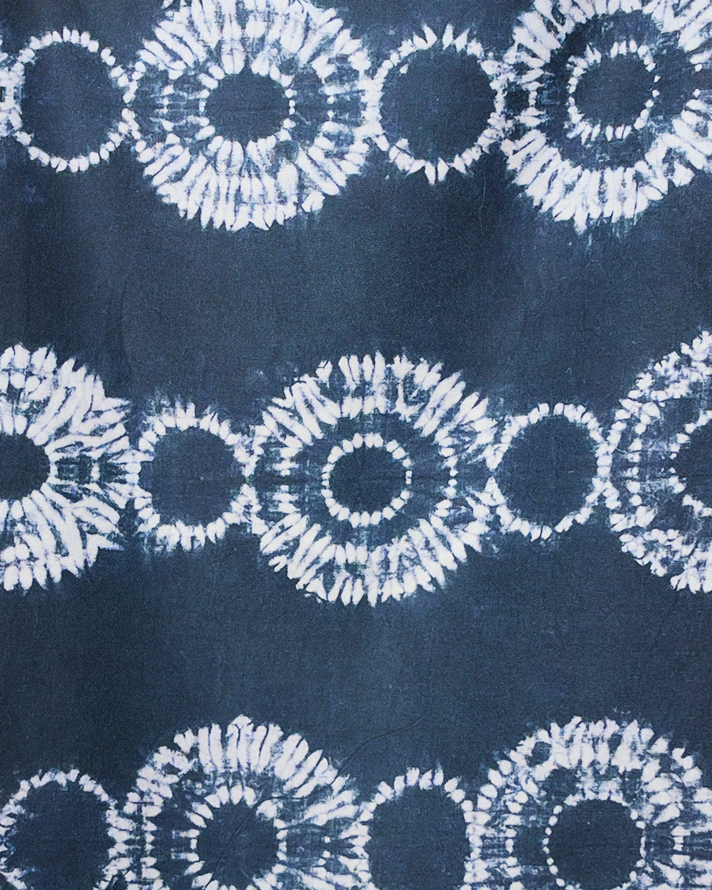 The GEOMETRY Shibo Stars micro-loop beach towel features abstract dark blue fabric with interconnected white tie-dye circles in horizontal rows, creating a striking geometric design that’s quick-drying and perfect for the beach.