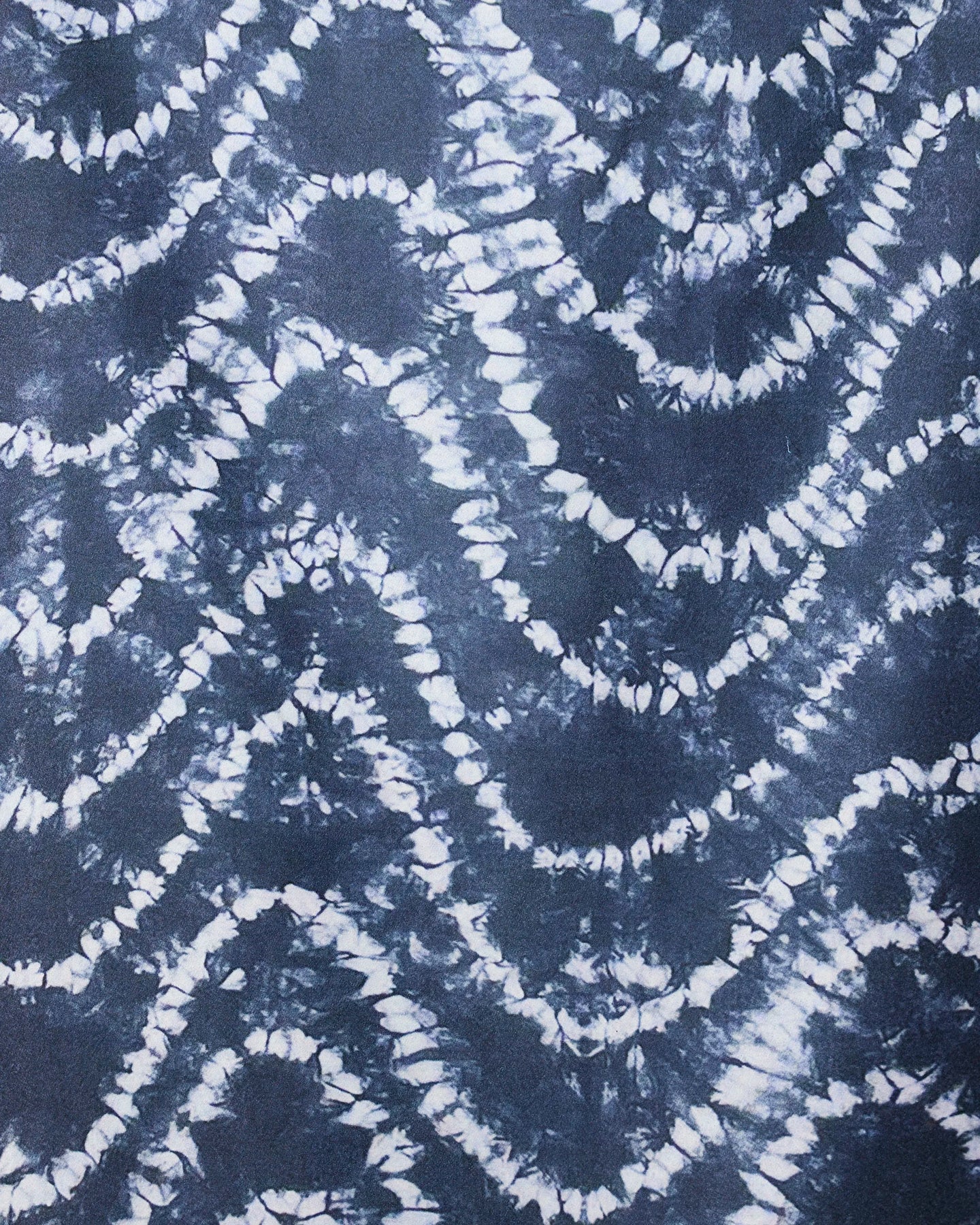 The GEOMETRY Shibo Waves Micro-loop Beach Towel features an abstract tie-dye pattern of dark blue and white zigzag waves. Its modern, textured design is perfect for quick drying and adding style to any beach day.