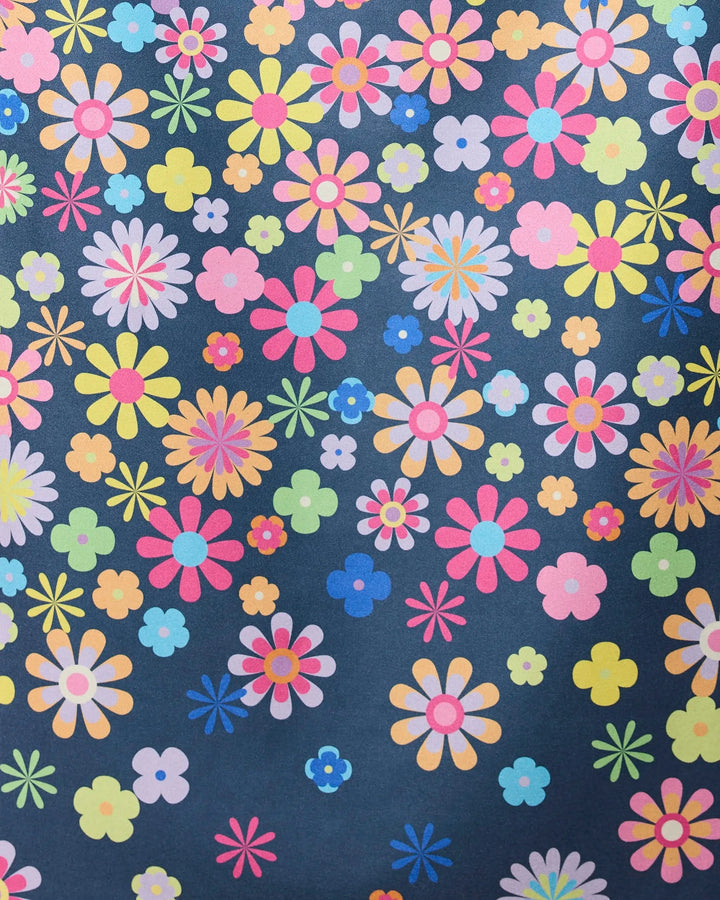 The Far Out Flowers Dark beach towel by GEOMETRY features quick-drying fabric and a bright, playful floral pattern with cartoon-style pink, yellow, blue, orange, and purple flowers on a dark background.