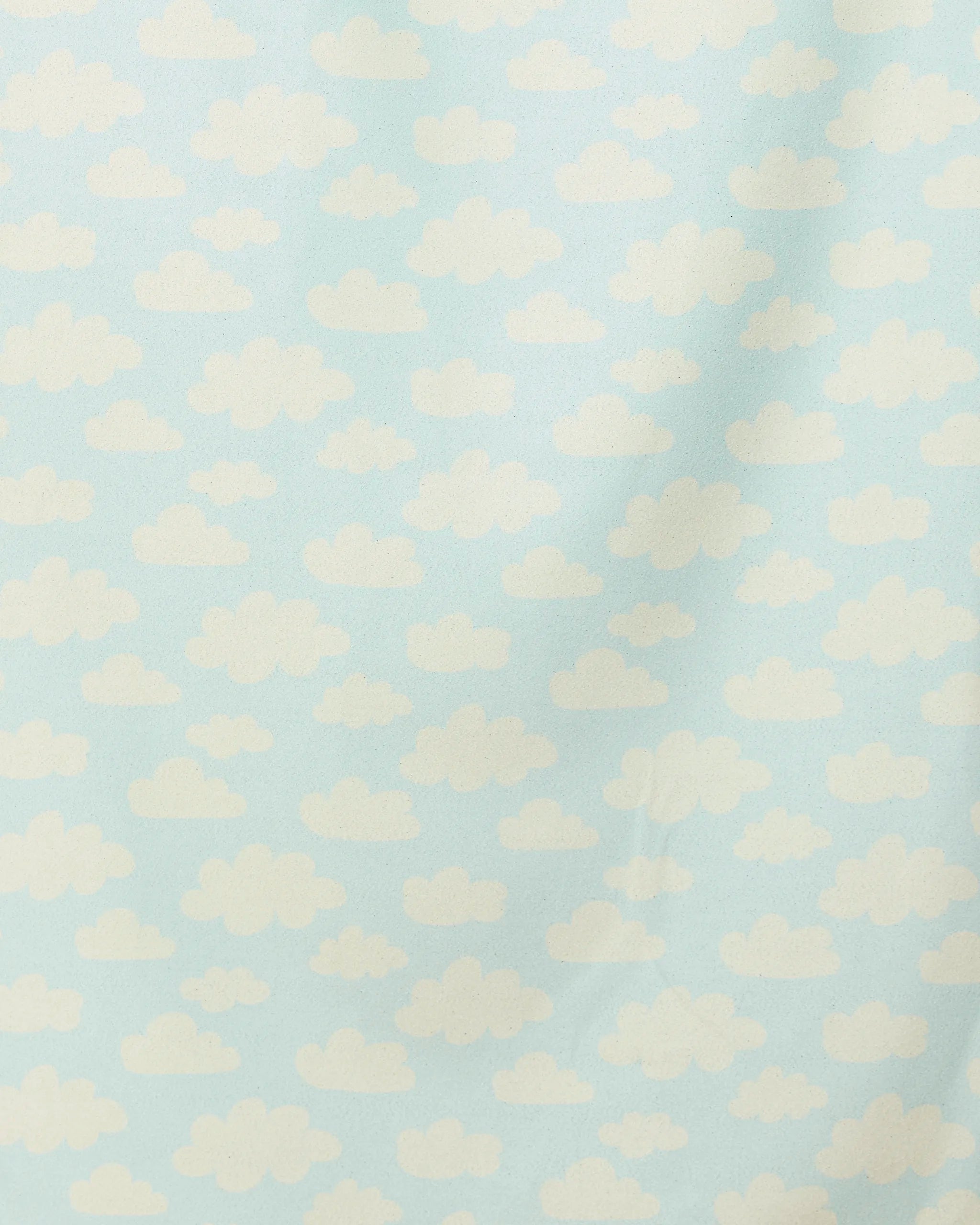 “Made In The Shade” by GEOMETRY features a light blue background with evenly spaced, fluffy white clouds—a whimsical pattern reminiscent of a cartoon sky. This quick-drying beach towel brings playful charm to your seaside days.