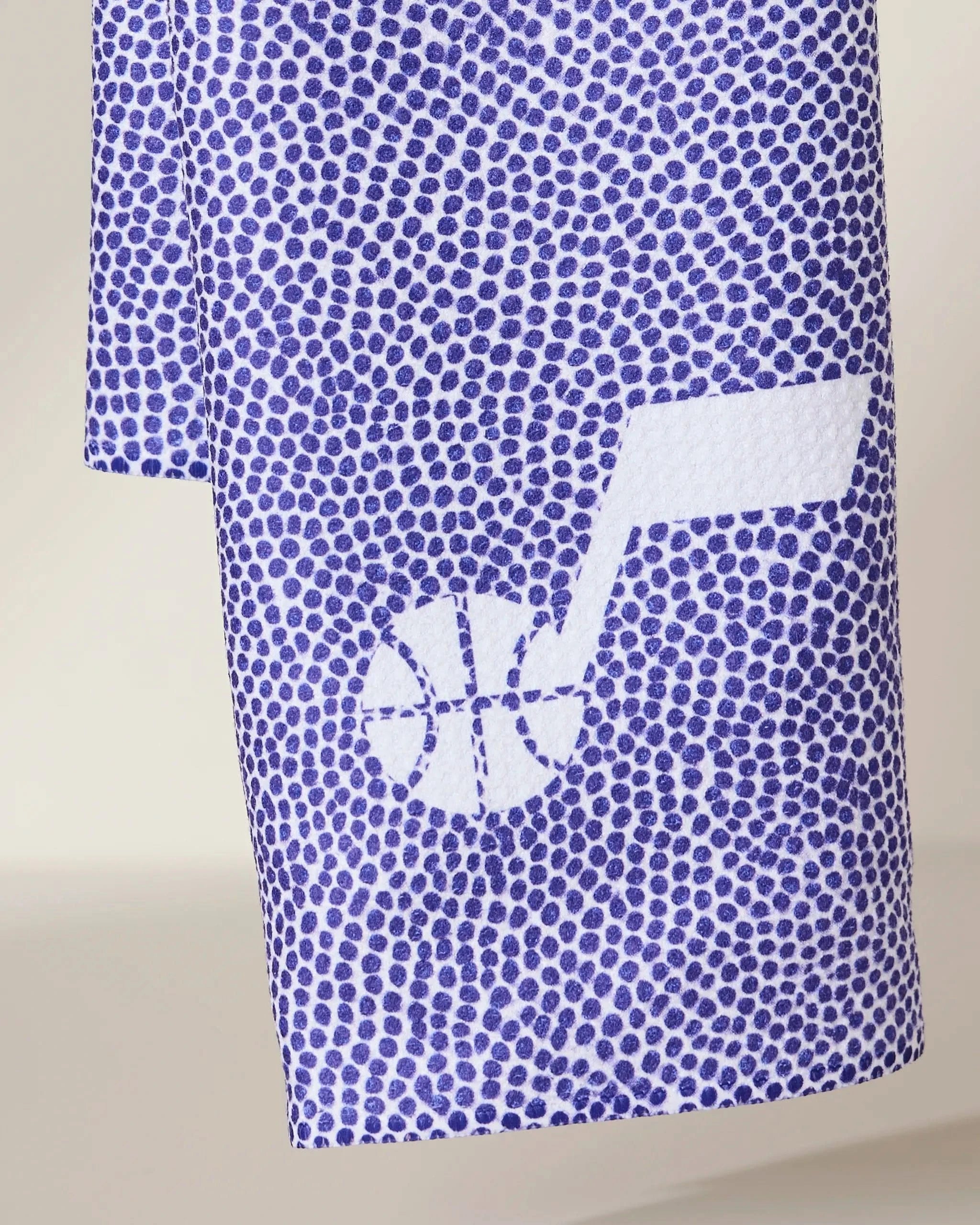 A close-up of Geometrys Jazz Grip, a blue and white towel featuring a textured, dotted pattern and a white basketball and musical note logo near the edge.