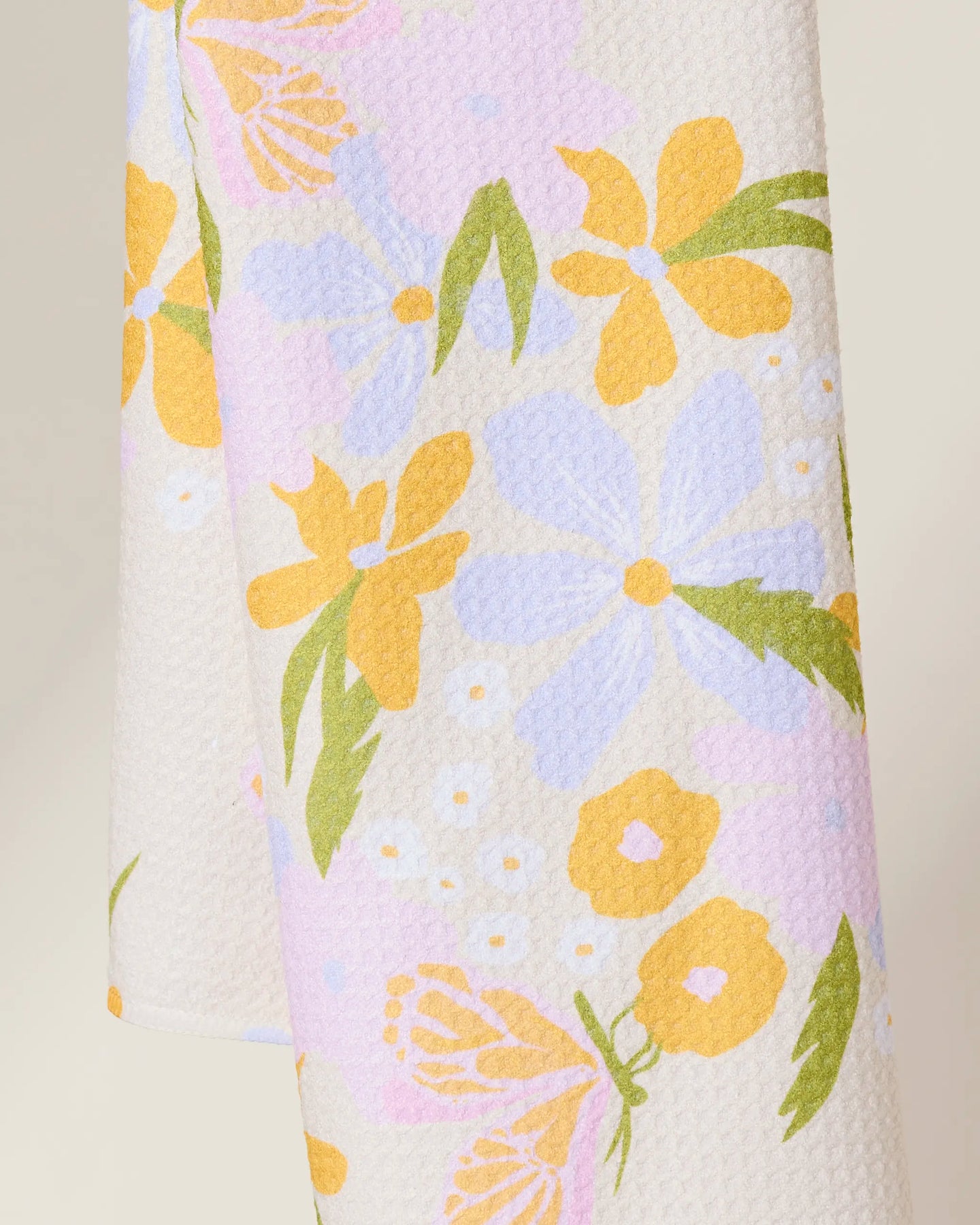 The GEOMETRY Abloom tea towel features a textured white fabric with a soft pastel floral pattern in yellow, light purple, pink, and green. Its ultra-absorbent design makes it both stylish and functional for everyday use.