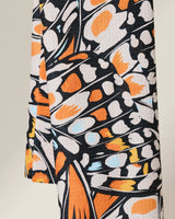 Close-up of GEOMETRYs Wings in the Wind towel, an ultra-absorbent piece featuring a vibrant abstract butterfly wing pattern in orange, black, white, and light blue. The textured fabric drapes beautifully to showcase its striking design.